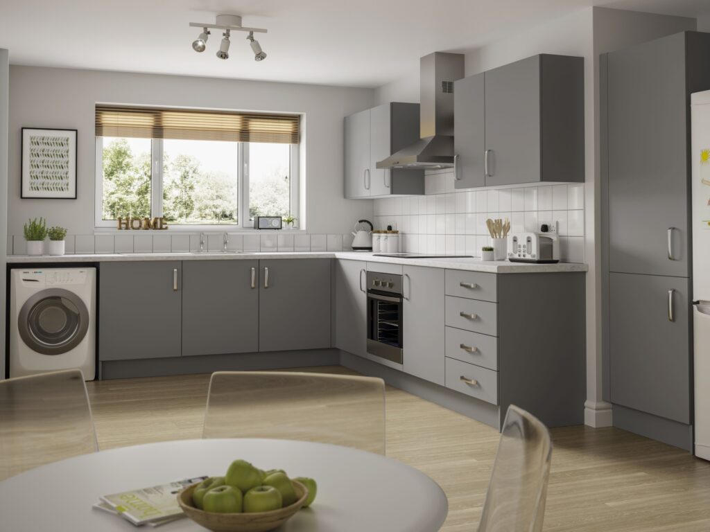 A dark shade of grey kitchen from Symphony Kitchens with a seletion of tall, base and wall cabinets. Image includes a dining table, cooker, washing machine and fridge freezer